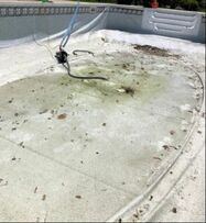 Pool in Little Rock Arkansas in need of repair, with leaves and drained with a pump inside removing the current bad water